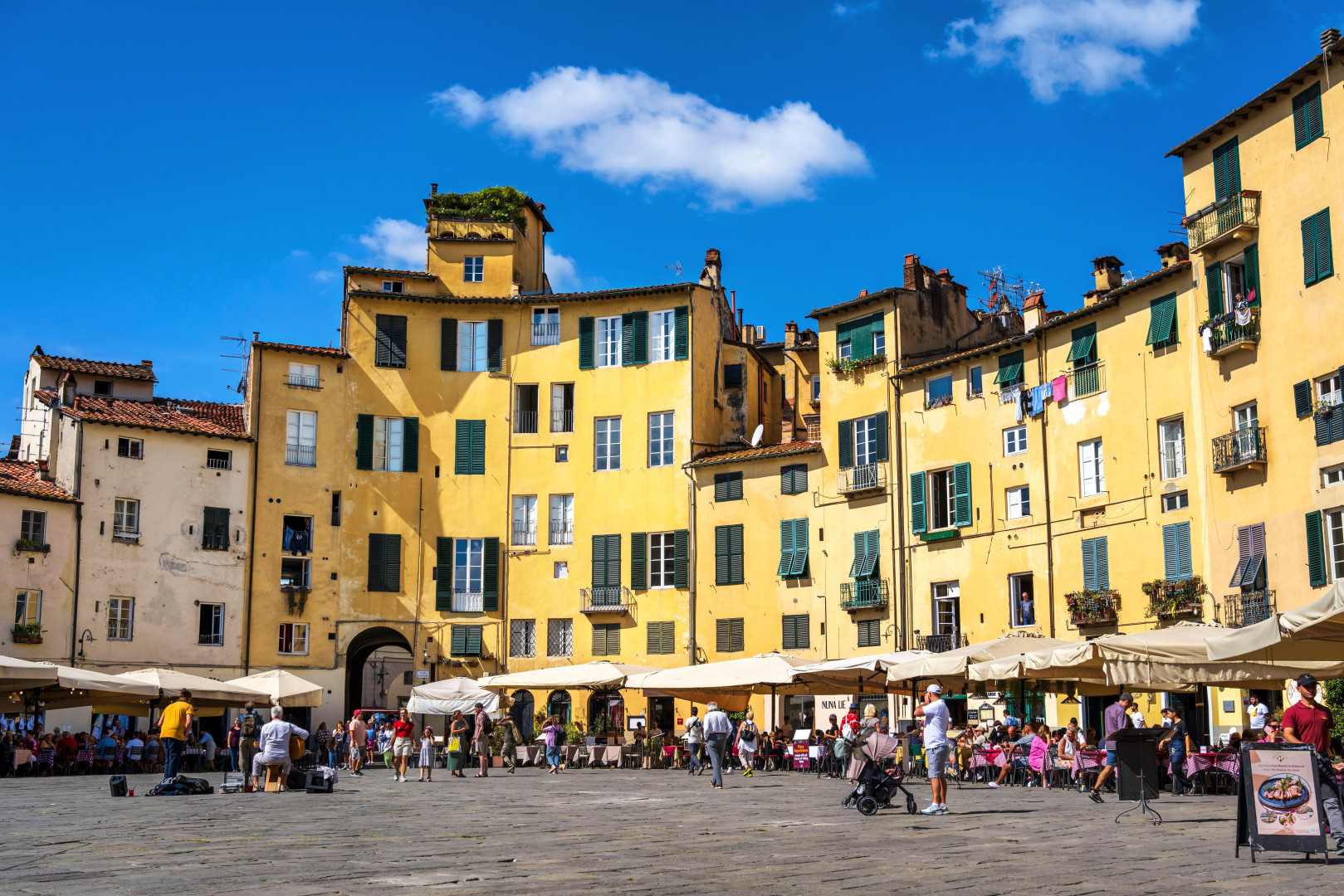 Vibrant piazza in Lucca, Tuscany, featuring al fresco dining and stunning architecture.