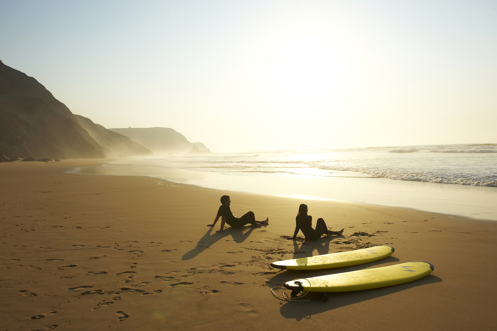Guests with surfboards on the beach at Martinhal Sagres resort in the Algarve, Portugal