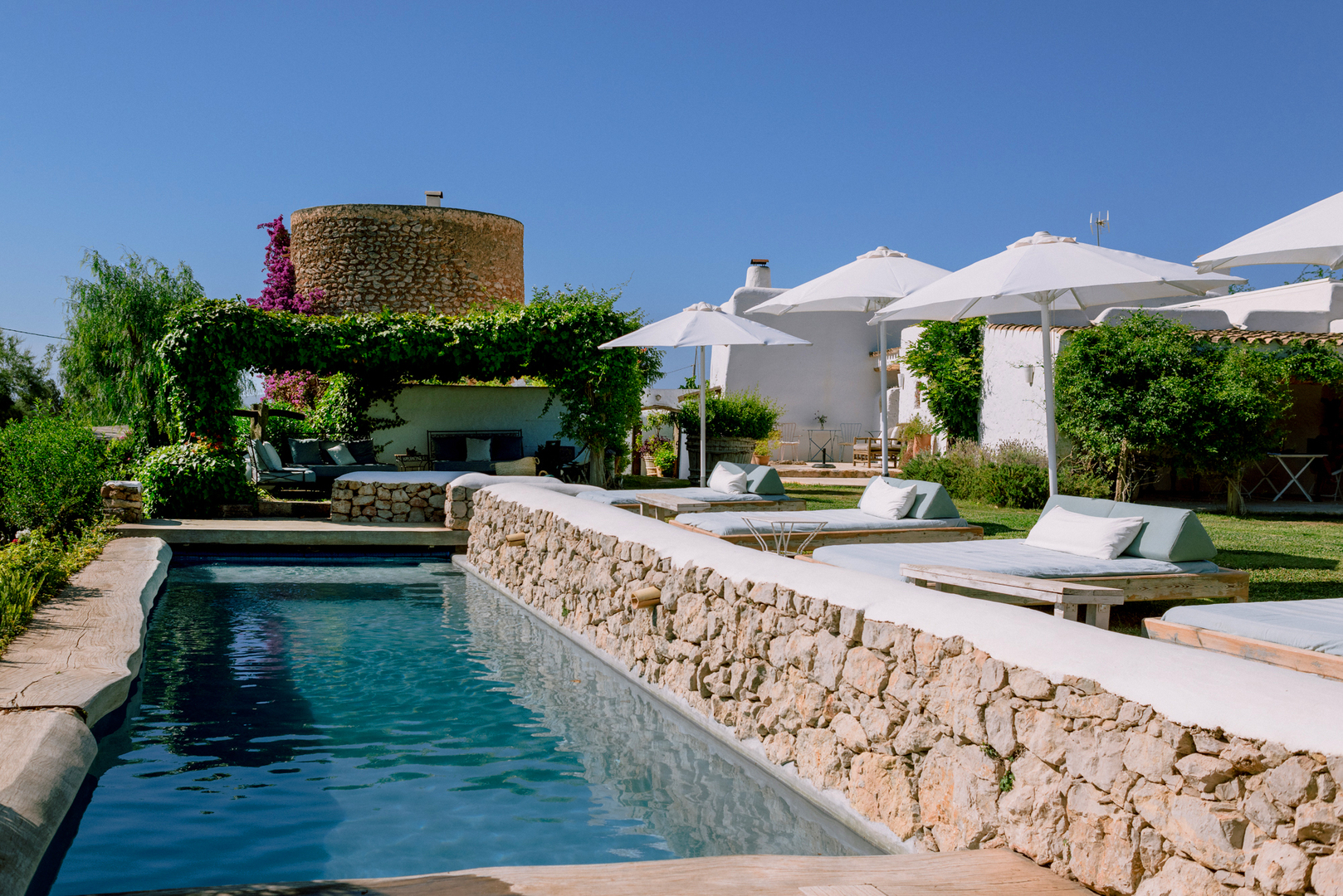A natural-style outdoor pool lined with loungers at Can Quince de Balafia, Sant Llorenc de Balafia, one of the best hotels in Ibiza