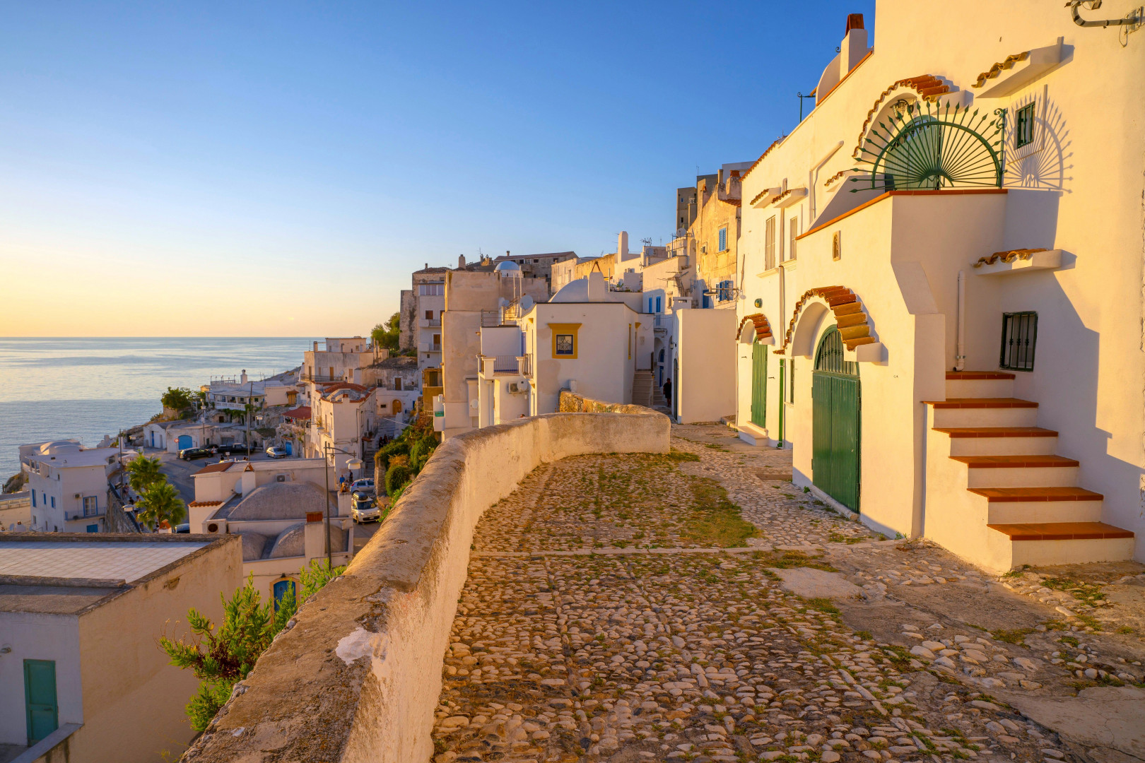 Charming whitewashed buildings perched above the sea in Peschici, Italy.