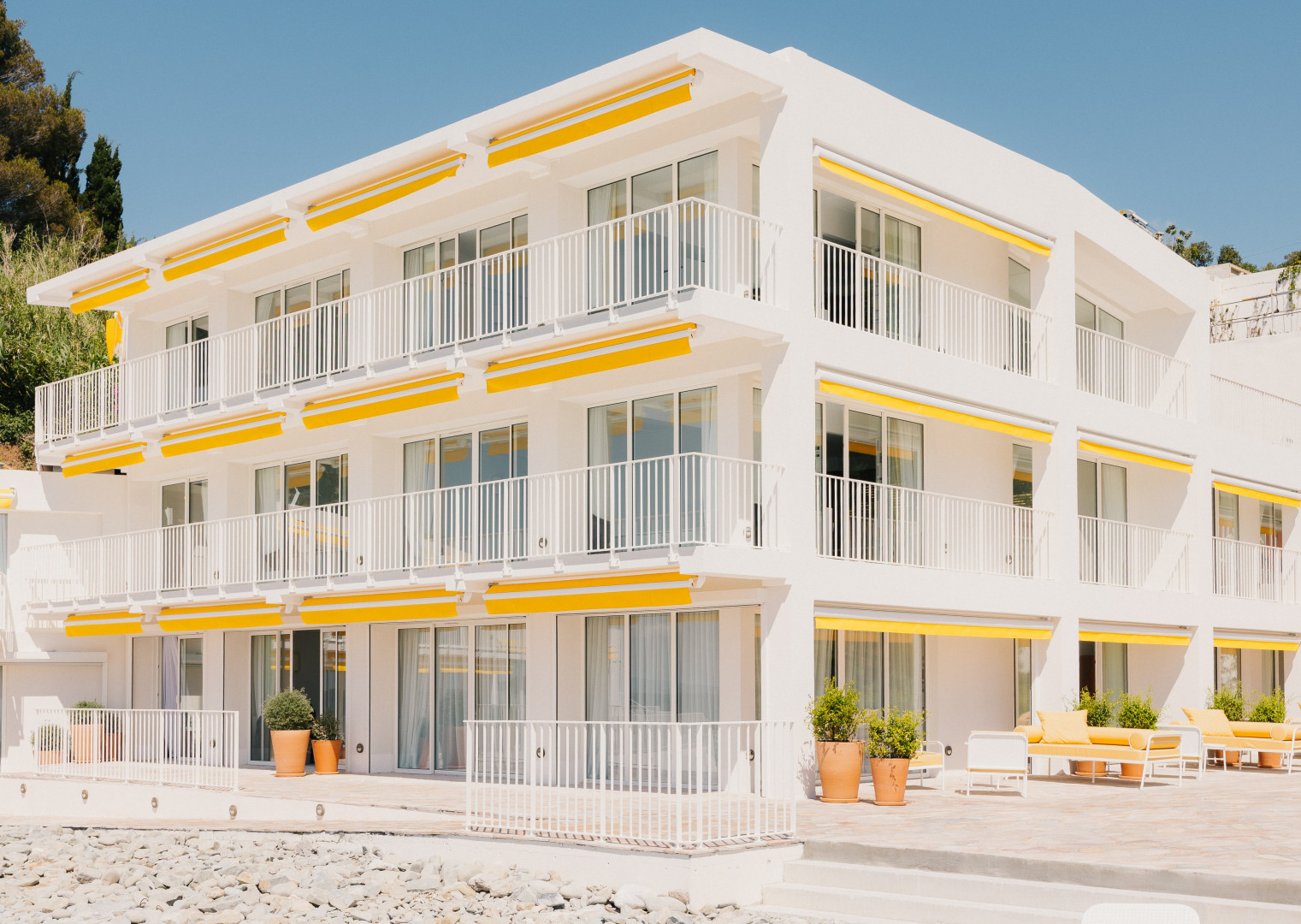 White building with yellow awnings and balconies.