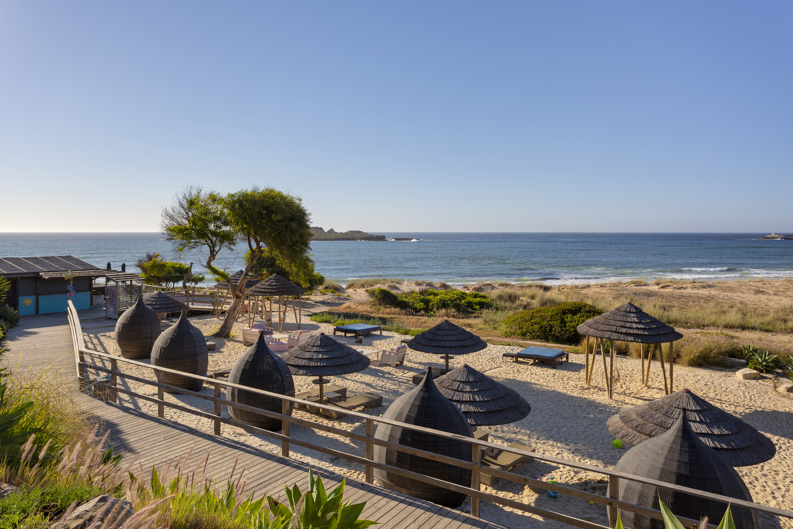 The beach hangout with thatched umbrellas and loungers at Martinhal Sagres resort in the Algarve, Portugal